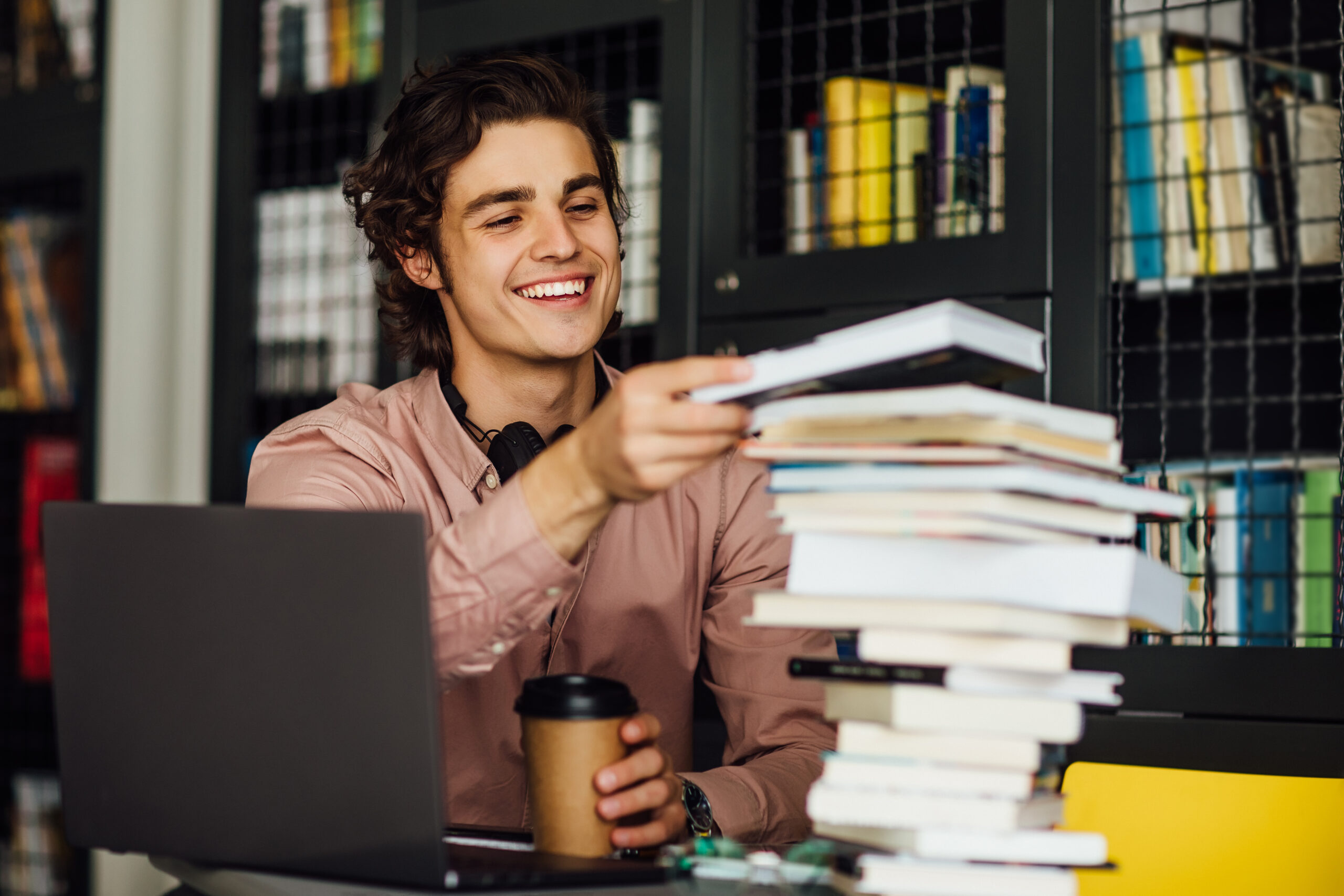 intellectual-man-reading-book-sitting-library-front-bookshelves-with-cup-coffee-hands